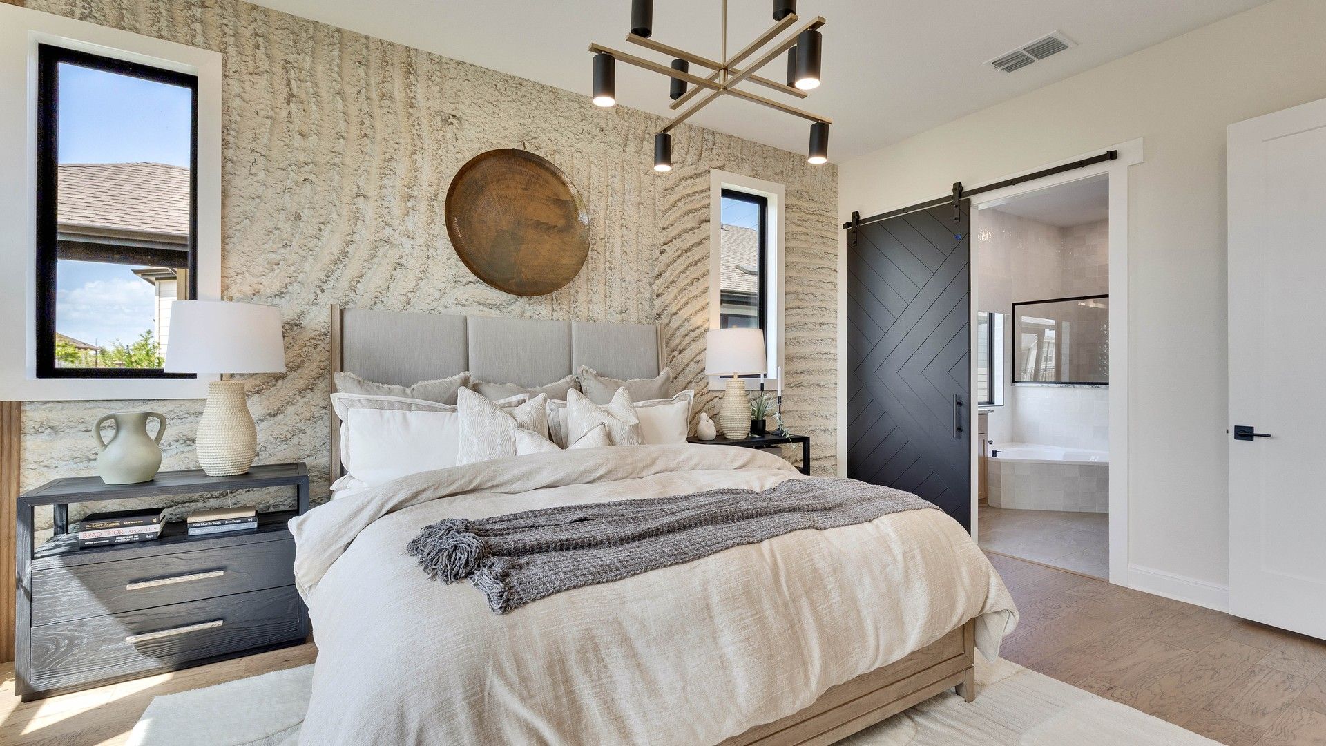 Experience refined elegance with textured walls and stylish barn door in Lakeside Meadows bedroom.