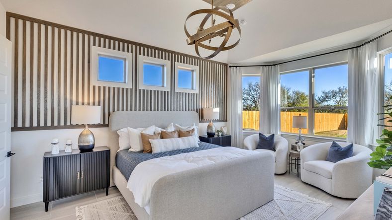 Experience sophistication in this Creeks Crossing bedroom featuring a wood accent wall and stunning lighting.