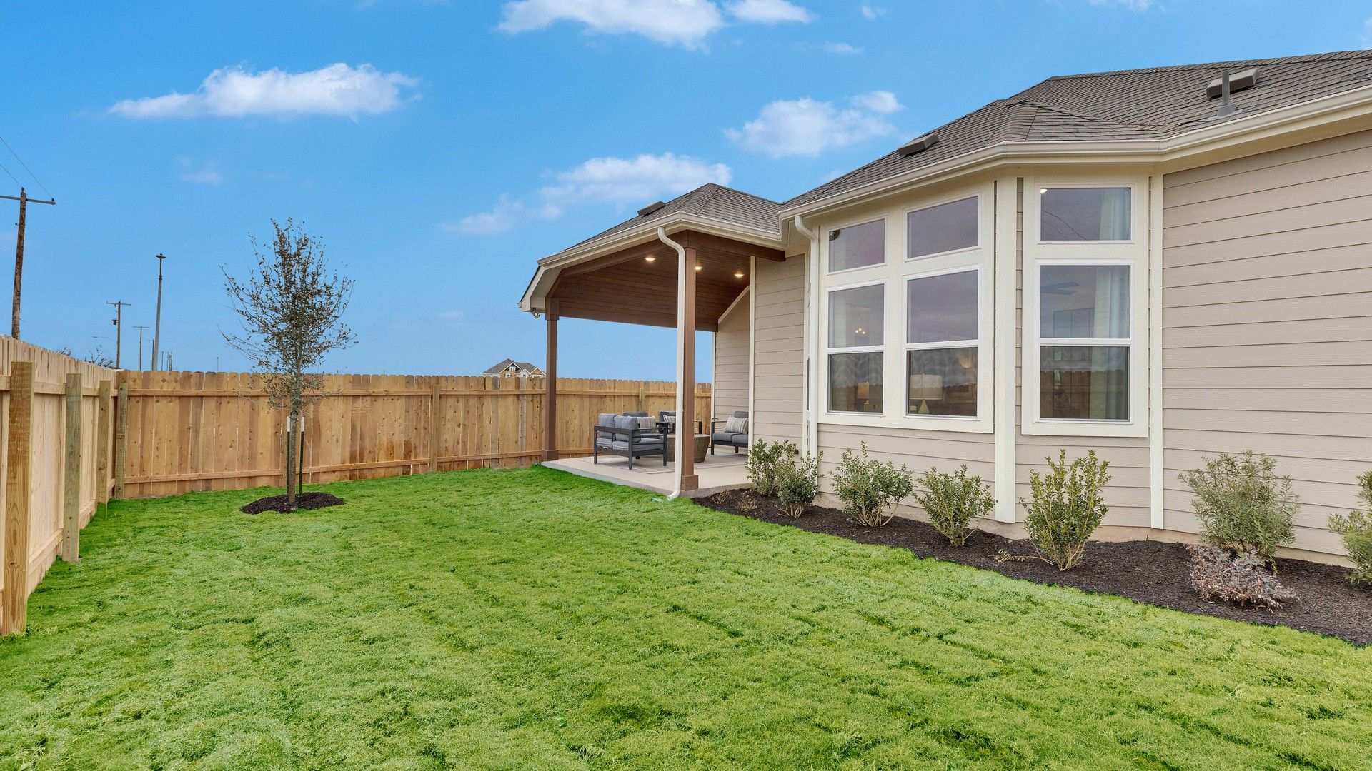 Elegant single-story home with expansive windows and refined covered patio area in Spring Creek.