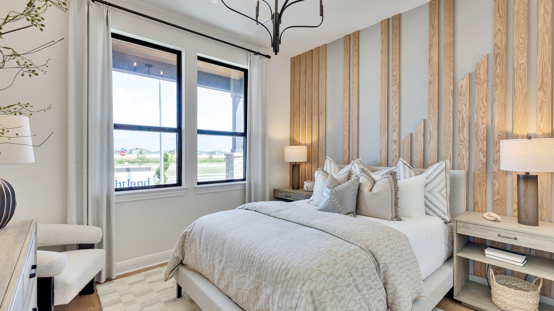Sophisticated bedroom featuring custom wood wall design, designer chandelier, and serene views in Lakeside Meadows.