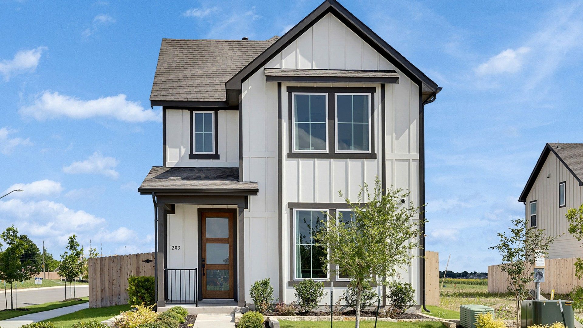 Elegant double-story home features a striking white facade with expansive windows. Located in Spring Creek.