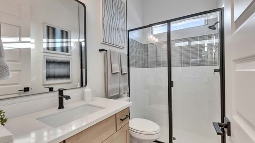 Elegant bathroom features a frameless glass shower, sleek black fixtures, and a luxurious wood vanity in Creeks Crossing.