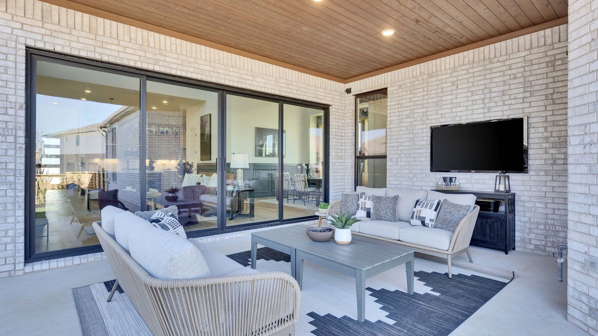 Luxurious patio featuring sleek white brick, plush seating, and expansive glass doors in Flora community.