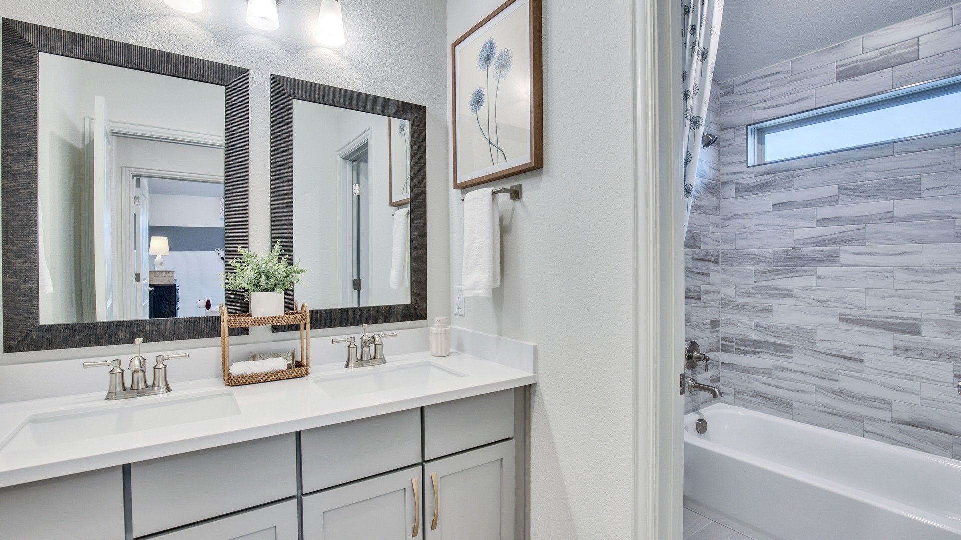 Elegant dual vanity features sleek hardware and artistic tile in Opal Ranch's luxurious bathroom suite.