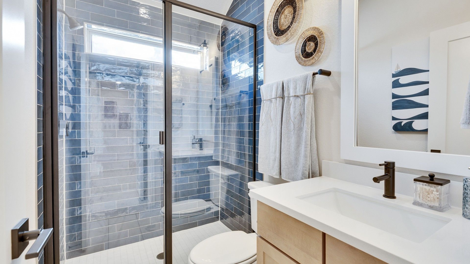 Experience opulent relaxation in this Sunfield bathroom, featuring elegant blue tile and refined wood cabinetry.
