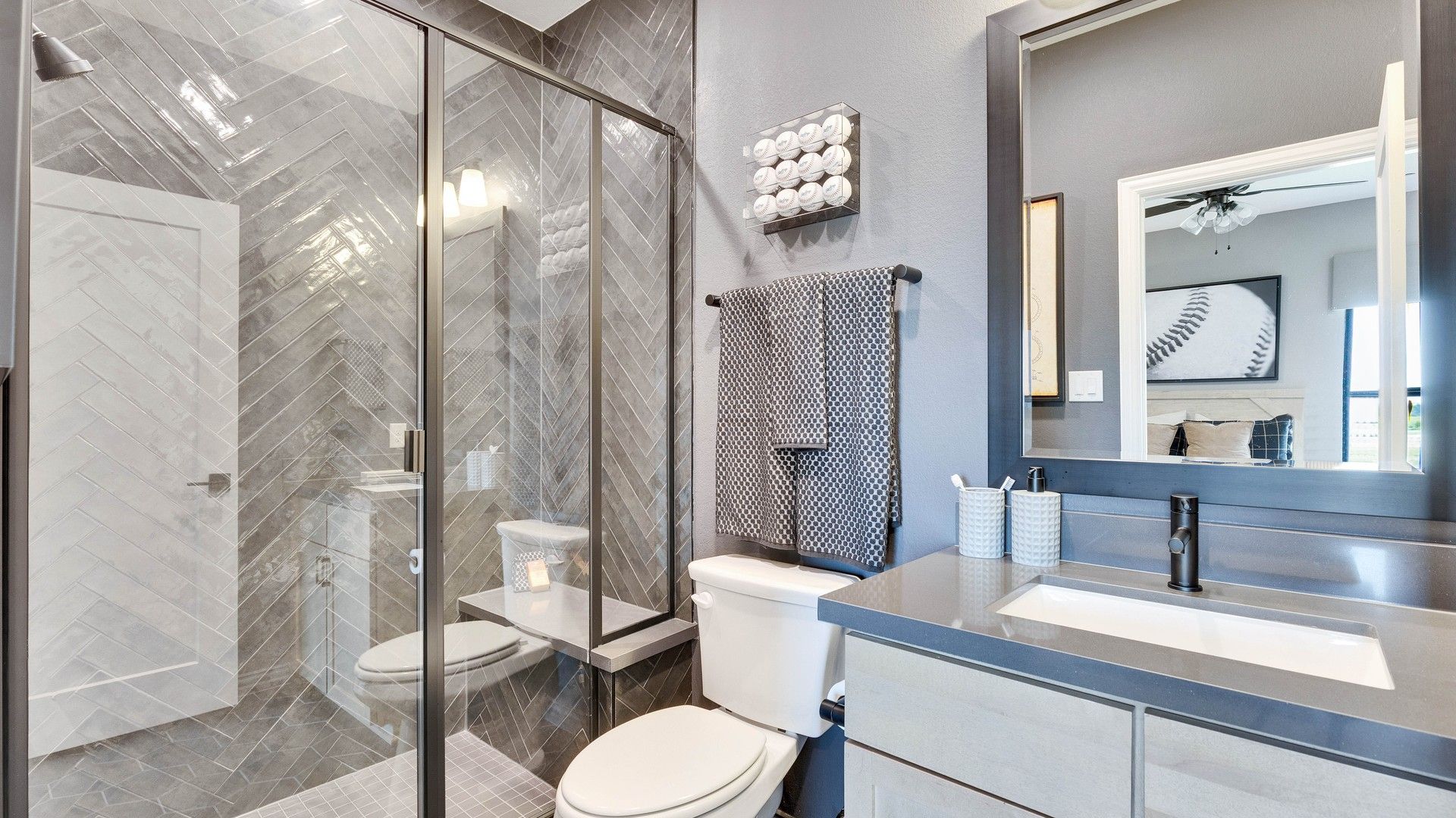 Elegant herringbone shower and contemporary dark vanity elevate this Lakeside Meadows bathroom.