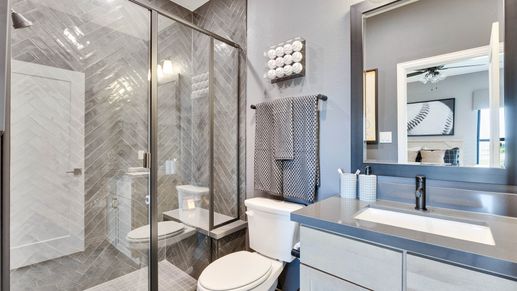 Elegant herringbone shower and contemporary dark vanity elevate this Lakeside Meadows bathroom.