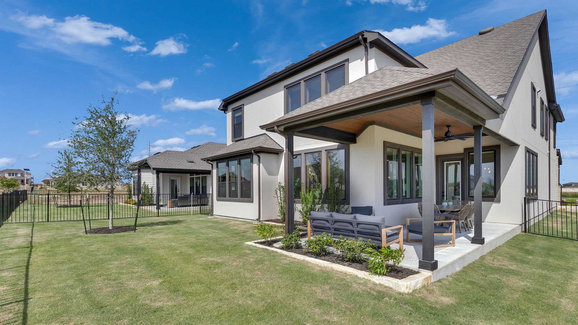 Elegant covered patio, expansive windows, and manicured lawn in exquisite Lakeside Meadows location.