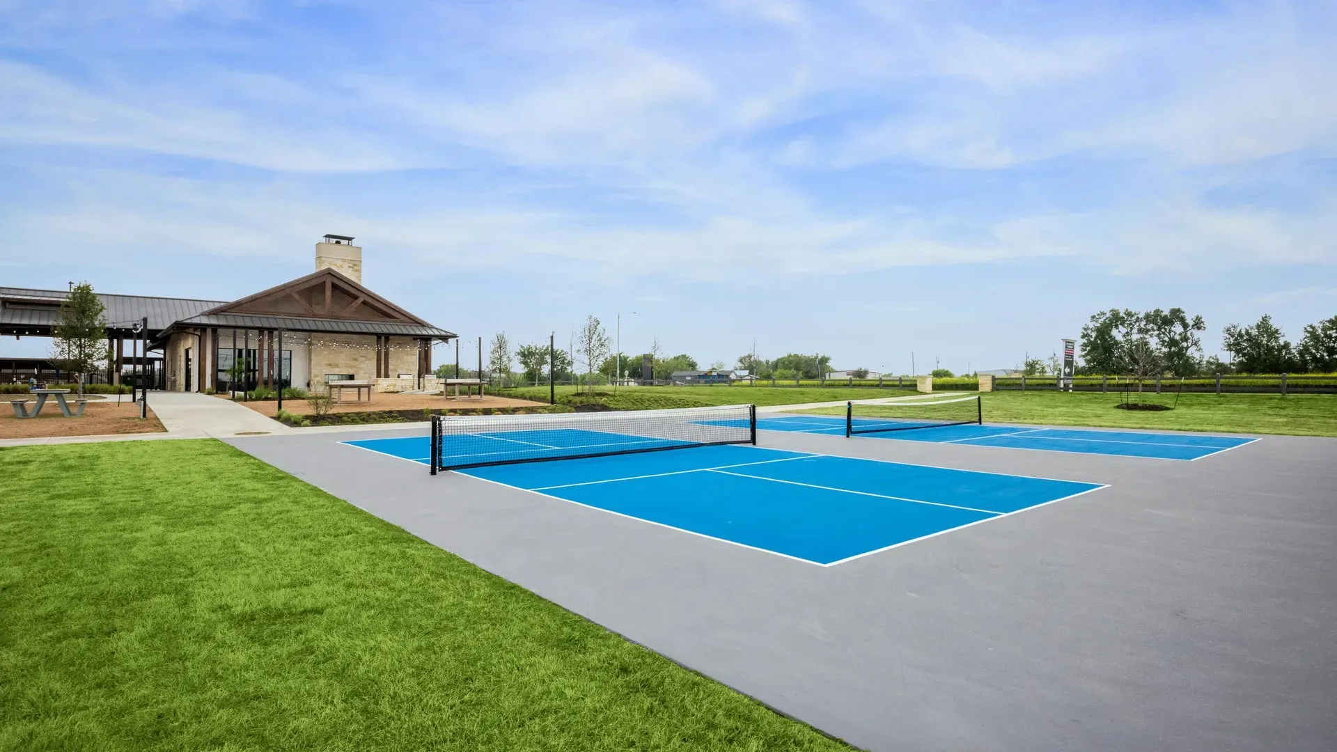 Elegant clubhouse with a brick facade and tennis courts in Carillon, Texas. Luxurious recreational amenities.