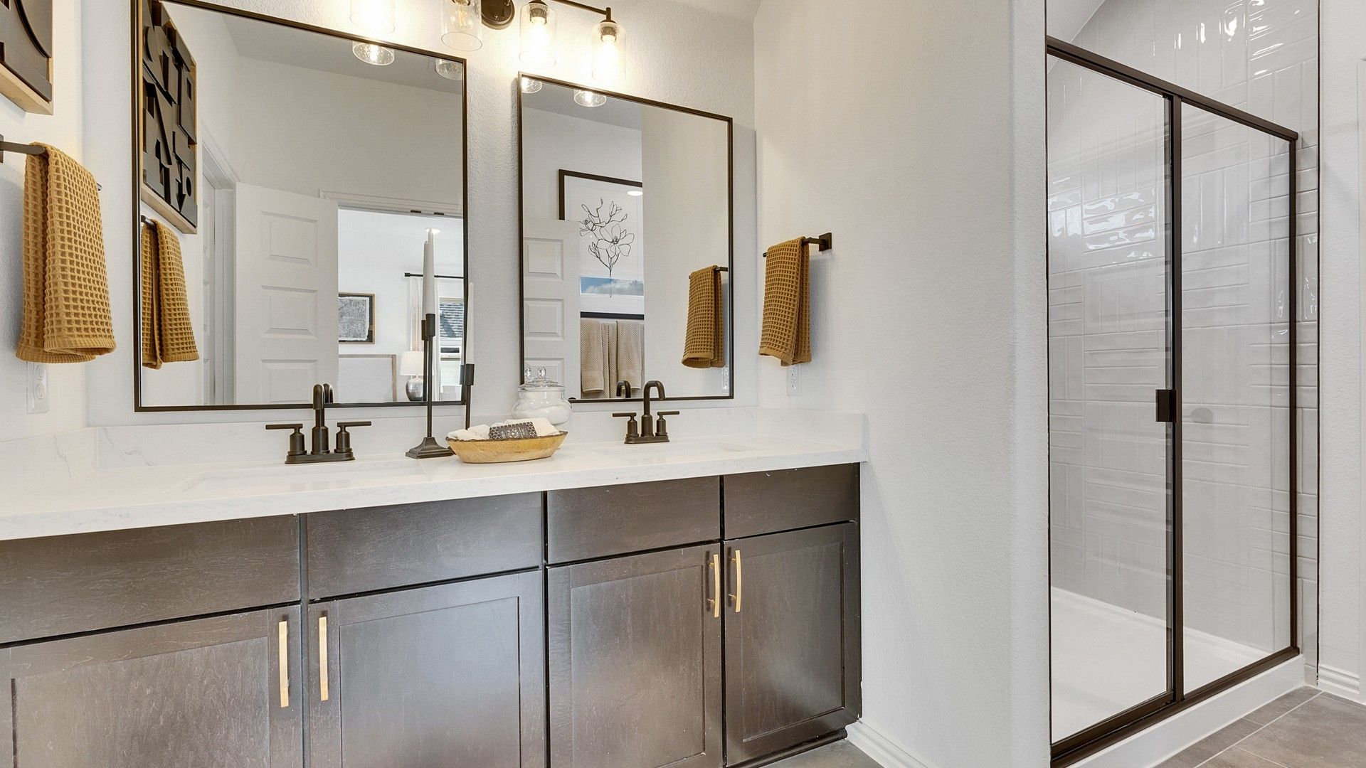Elegant dual-sink vanity, dark wood cabinetry, pristine glass shower in Spring Creek enhances luxury living.