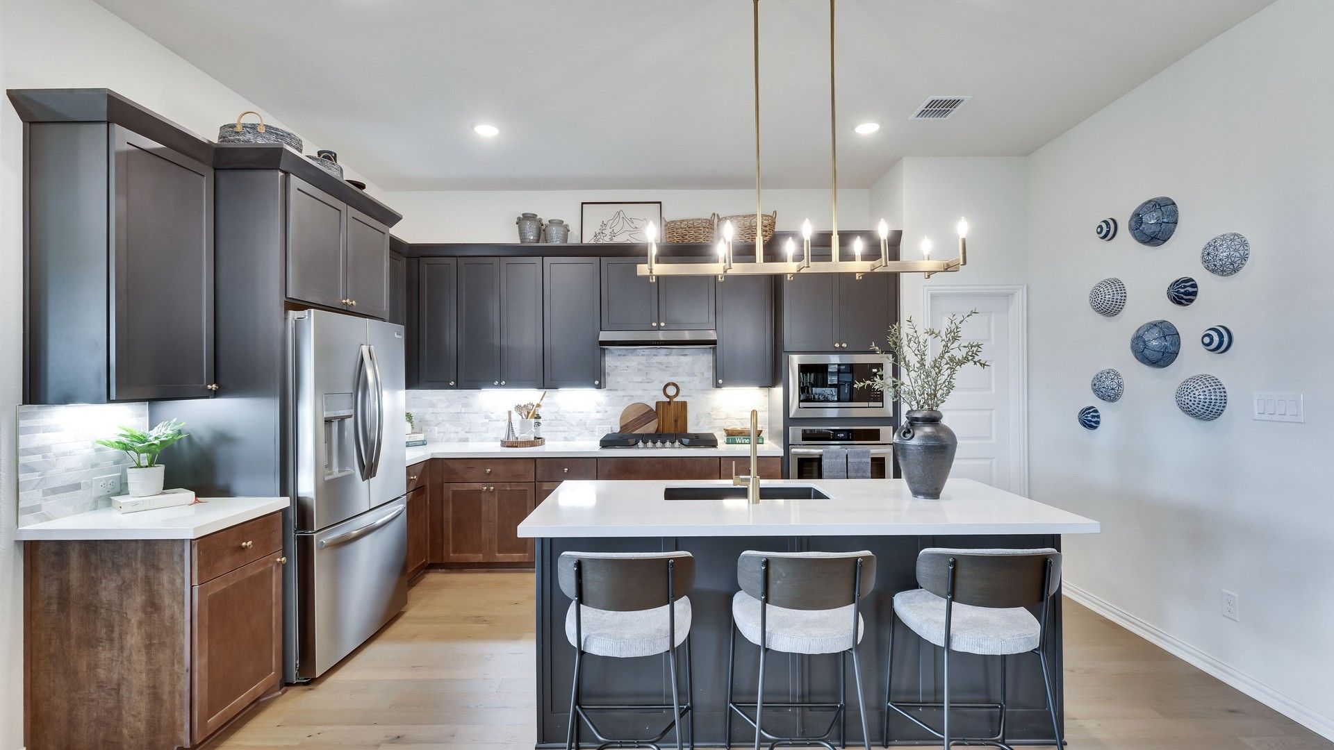 Sophisticated dark cabinetry with brass fixtures and a sleek island elevate this Lakeside Meadows kitchen.