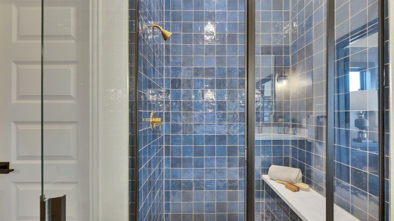 Indulge in this sophisticated shower with exquisite blue tiles and brass details in Lakeside Meadows.