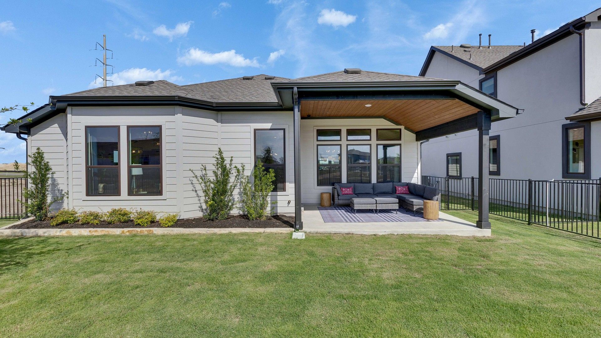 Elegant covered patio features premium seating and large windows in Lakeside Meadows. Fenced for privacy.