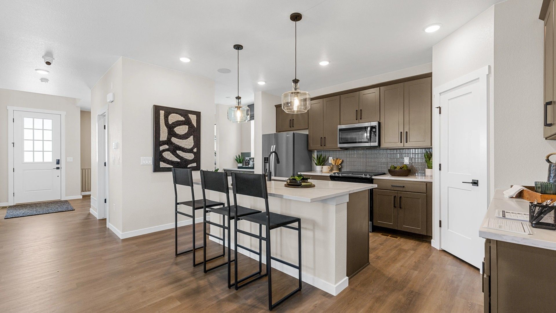 Elegant kitchen in Timnath Lakes showcases hardwood floors, sleek cabinetry, and designer pendant lighting.
