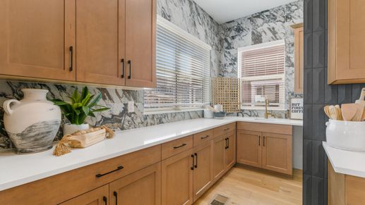 Dillon Pointe kitchen showcases refined light wood cabinetry, exquisite marble backsplash, and ample natural light.