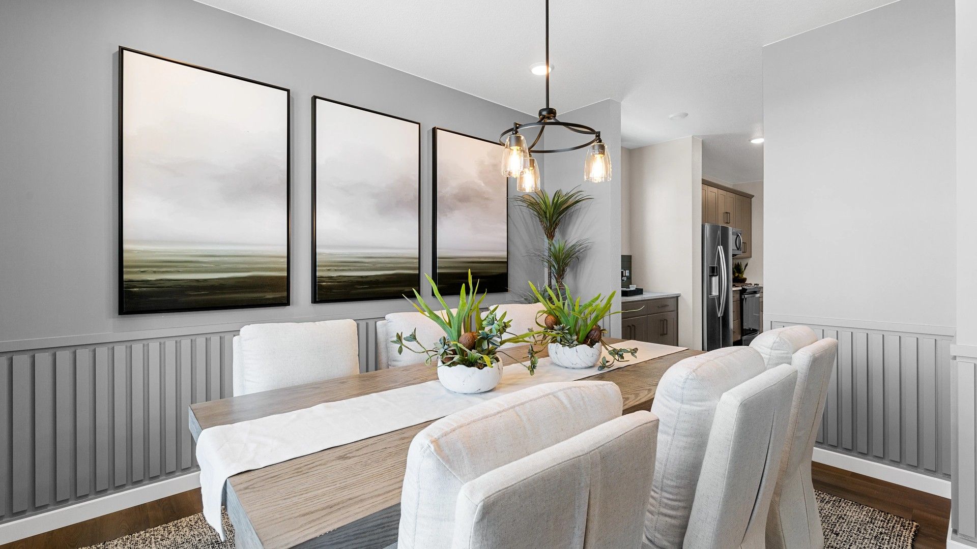 Experience luxury in Timnath Lakes' dining room, featuring abstract art, refined cabinetry, and elegant chandelier design.