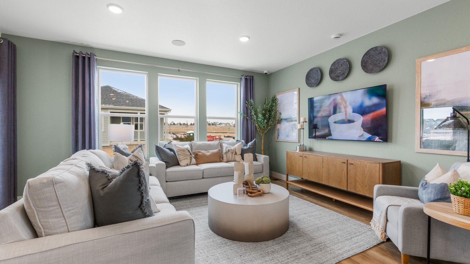 Spacious living room boasts sleek design, hardwood floors, and expansive windows in the Bloom Community.