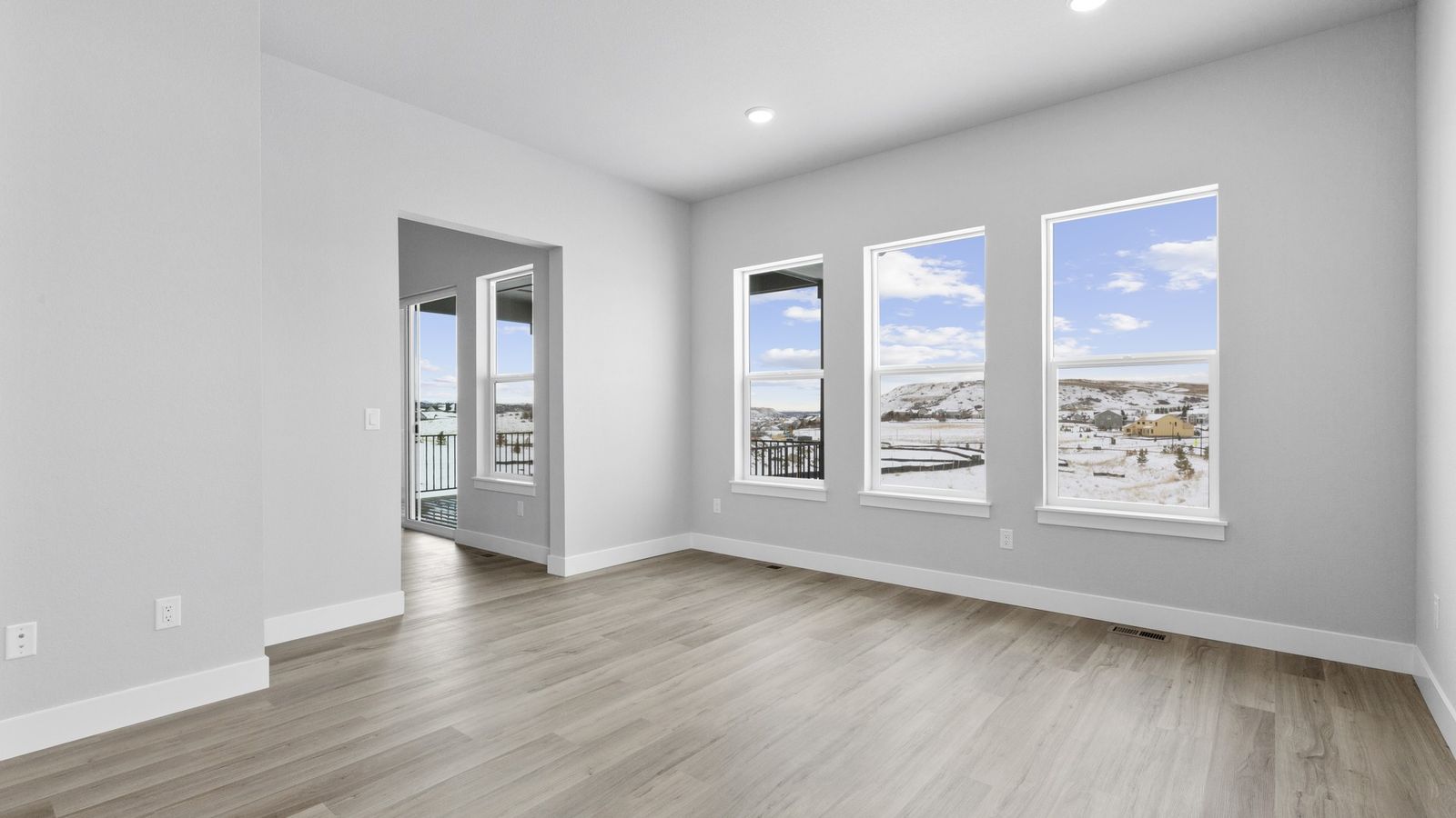 Elegant living room in Montaine with expansive windows and exquisite wood flooring, offering breathtaking mountain vistas.