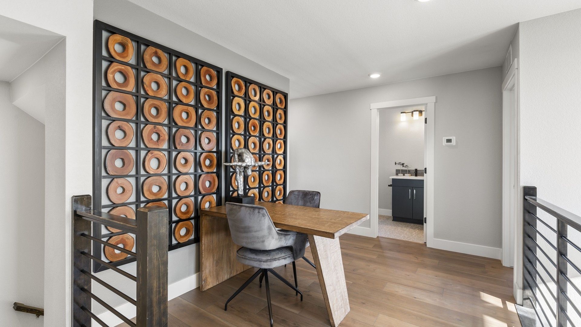 Elegant office boasts artistic wall installation, rustic wooden desk, and sleek railing in Dillon Pointe.