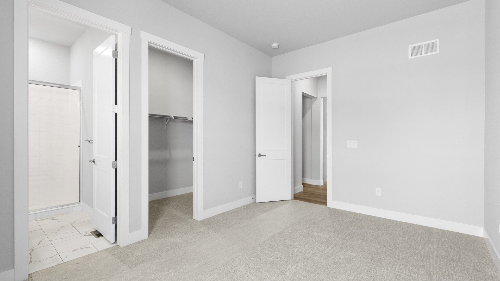 Chic Montaine bedroom features plush carpeting, sleek doors, and luxurious en-suite bath.