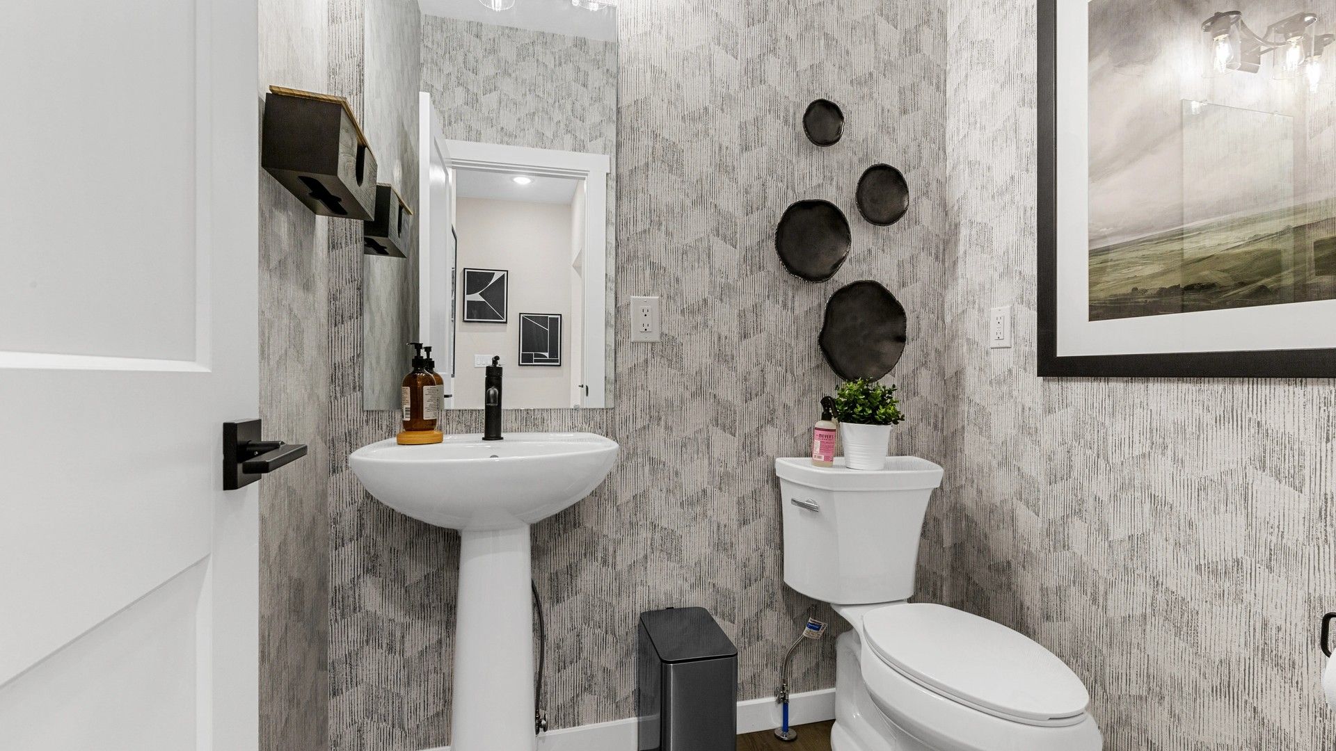 Elegant Timnath Lakes bathroom featuring geometric wallpaper, sleek pedestal sink, and modern decor elements.