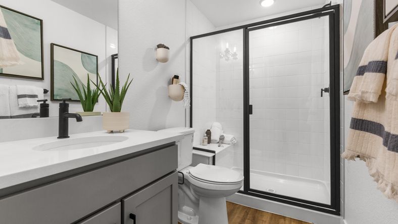 Elegant design featuring a frameless glass shower and rich wood flooring in sought-after Bloom community.