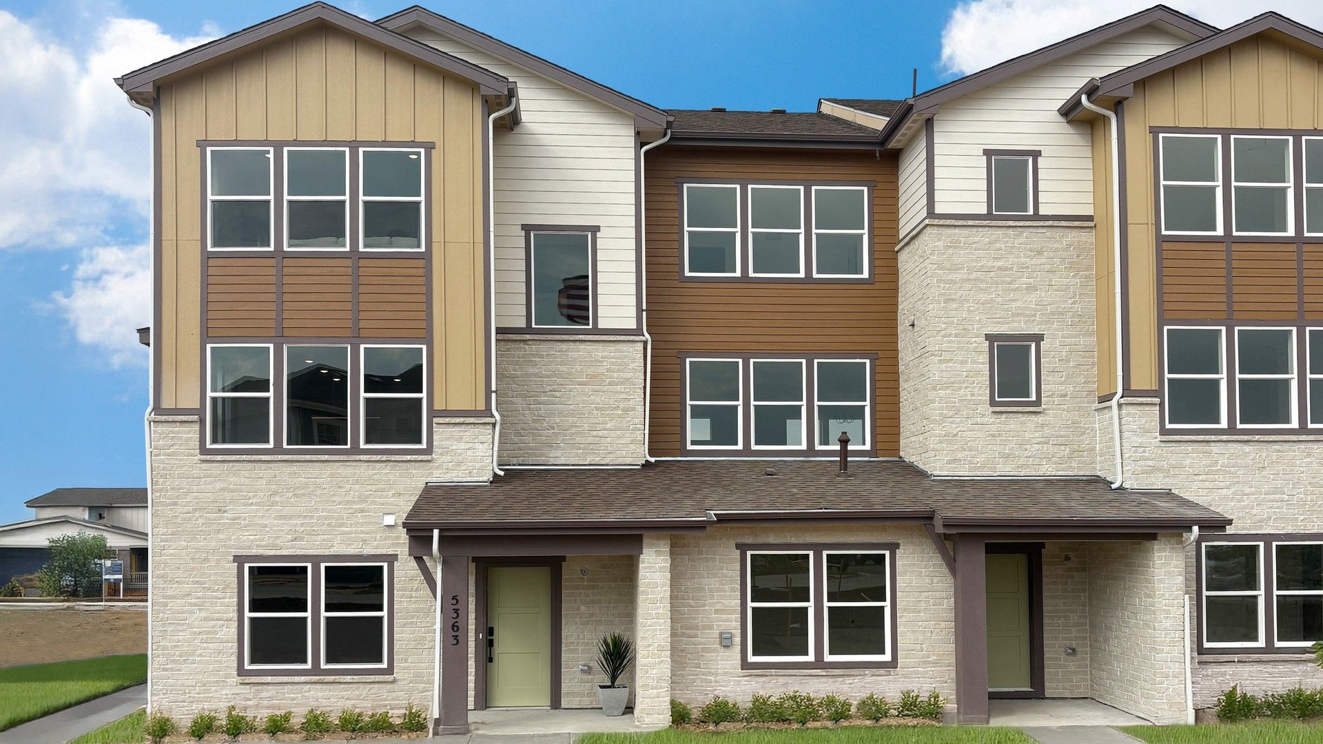 Luxurious Windler Townhomes boast expansive windows and elegant stonework in a serene suburban setting.