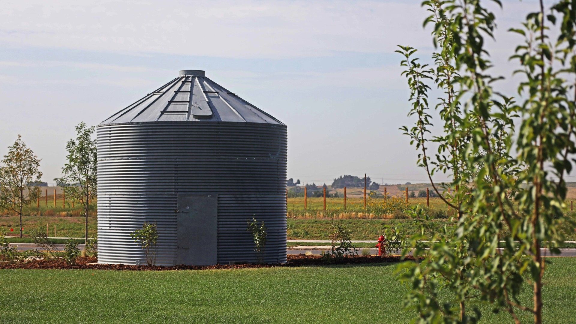 Elegant steel grain silo amidst verdant lawns defines Granary community's innovative architecture.