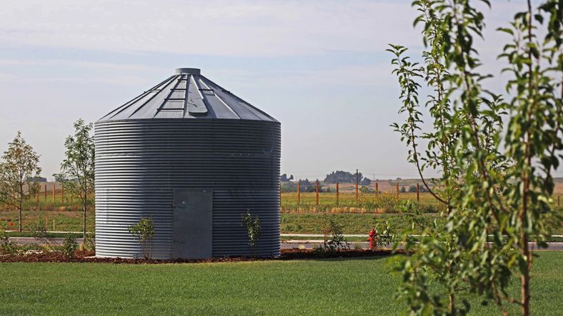 Elegant steel grain silo amidst verdant lawns defines Granary community's innovative architecture.