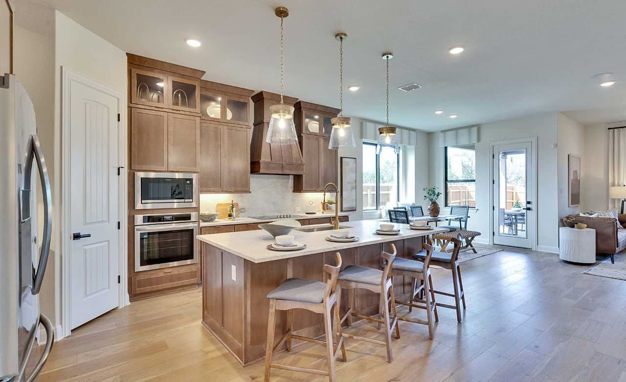 Luxurious wood cabinetry and exquisite pendant lighting define this Retreat at San Gabriel kitchen.