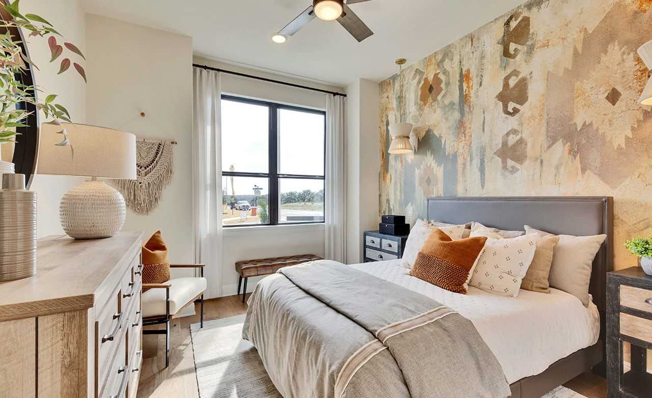 Exquisite textured accent wall and sleek lighting elevate this bedroom at Retreat at San Gabriel, Texas.
