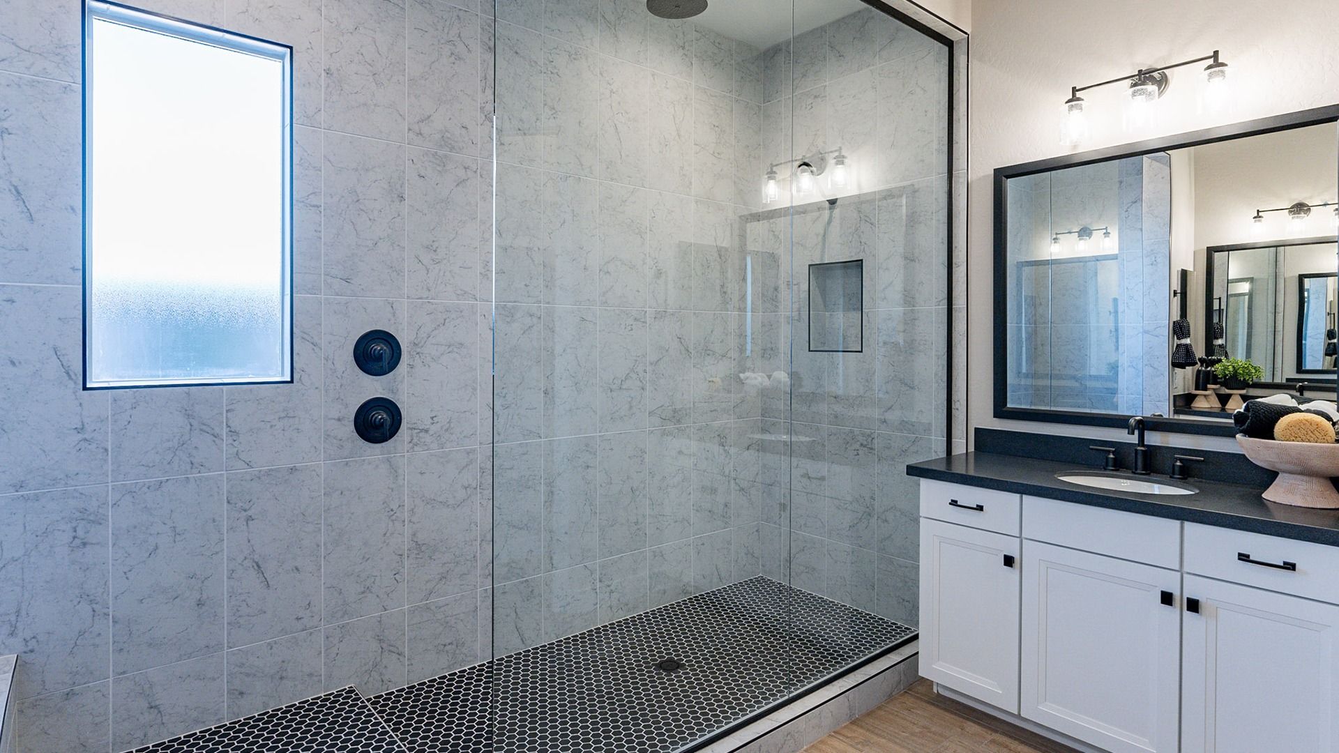 Experience opulence with marble shower tiles, sleek glass, and high-end black fixtures in Arroyo Seco.