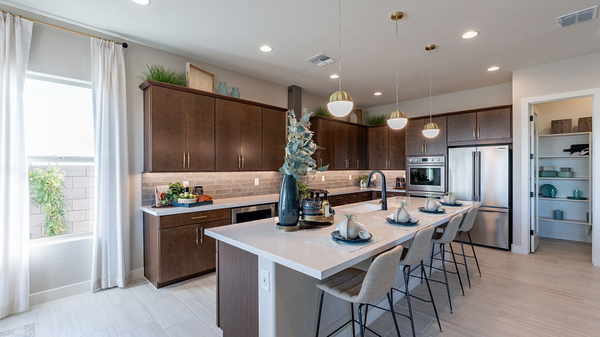 Elegant kitchen features sleek dark wood cabinetry, expansive island, and chic lighting. Arroyo Seco Hacienda luxury.