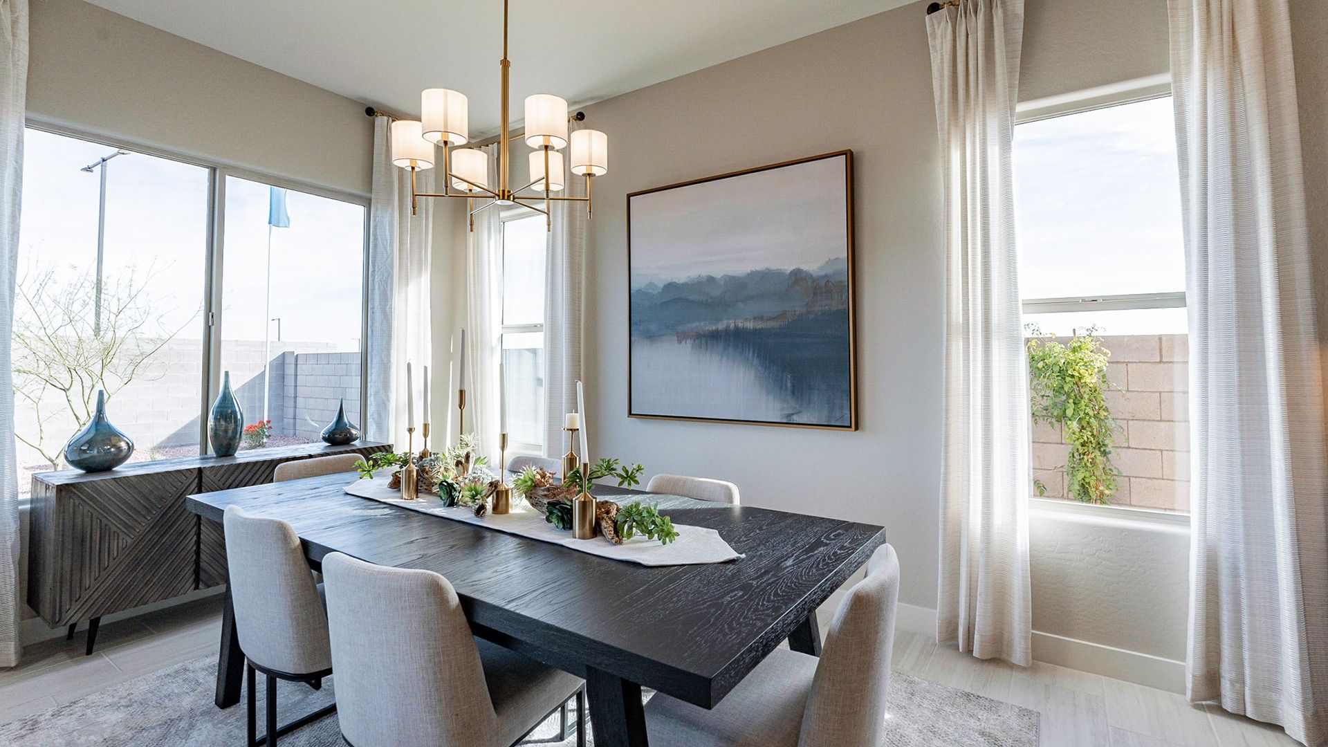 Experience refined elegance with a dark wood table, gold accents, and expansive windows in Arroyo Seco.