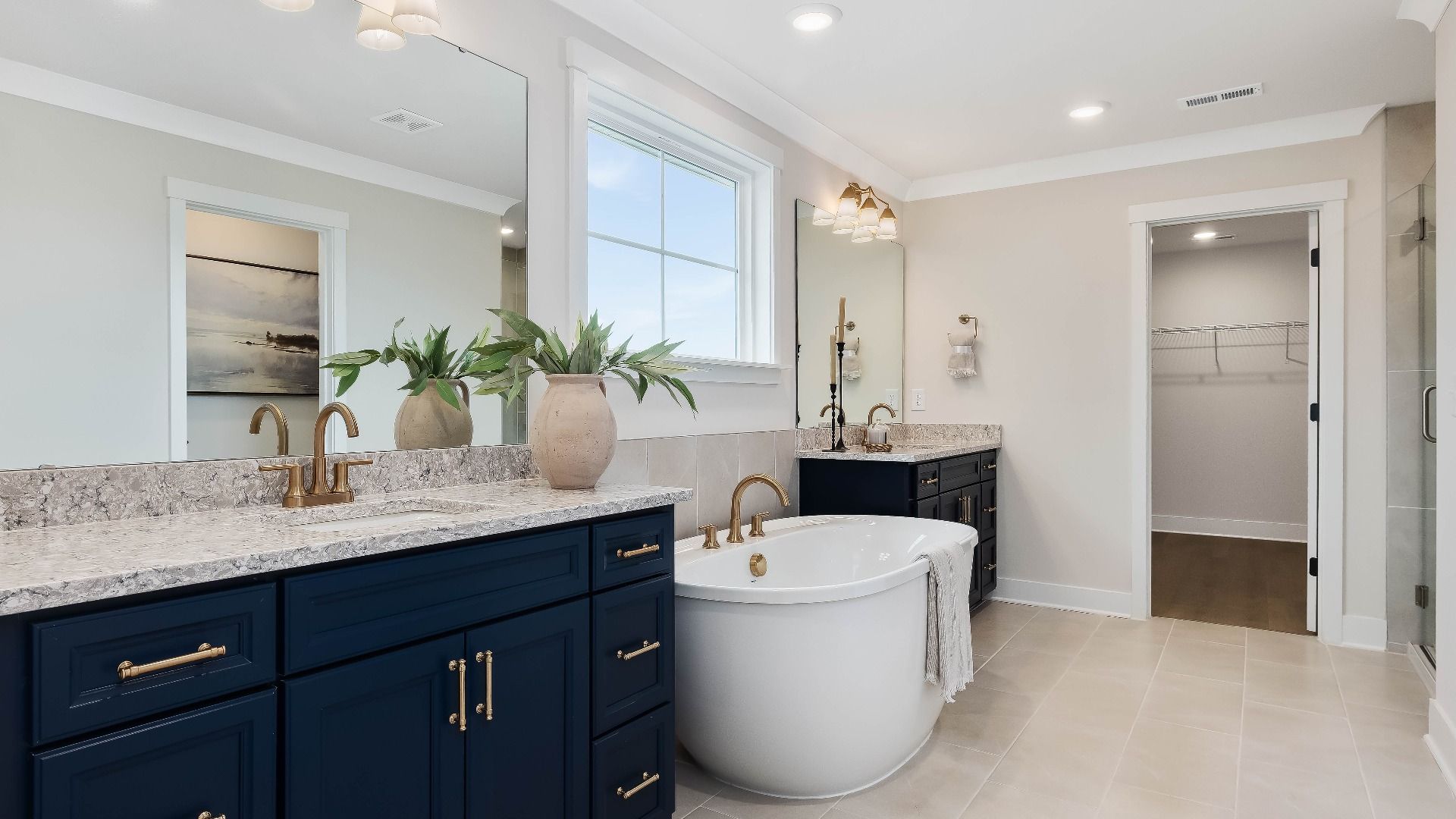 Stonefield home plan en suite primary bath with separate vanities, soaking tub and tile shower