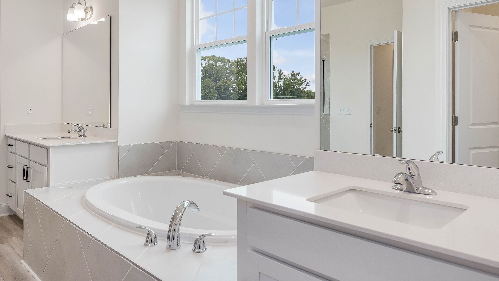 Stonehaven home plan primary bathroom with separate vanities, soaking tub, linen closet and tile shower
