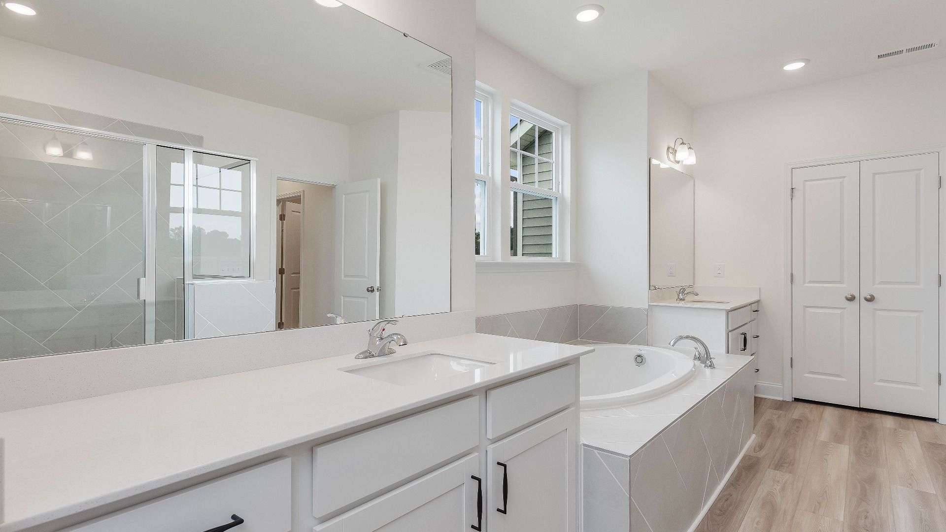 Stonehaven home plan primary bathroom with separate vanities, soaking tub, linen closet and tile shower