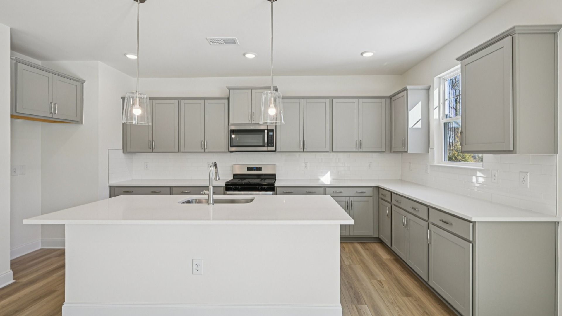 Wagener home plan spacious kitchen with island, tile backsplash, pendant lights, ample counter space and cabinetry