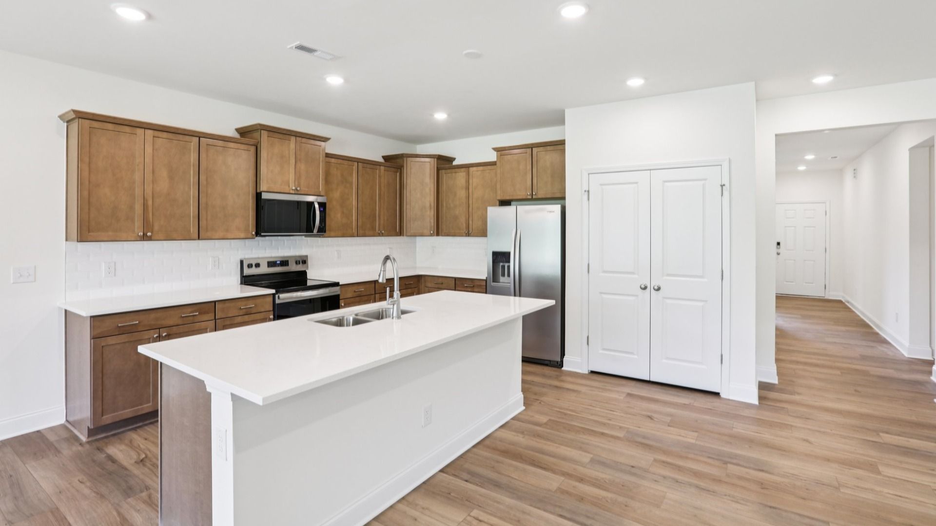 Pendleton home plan open concept kitchen with large island, tile backsplash and abundant cabinetry