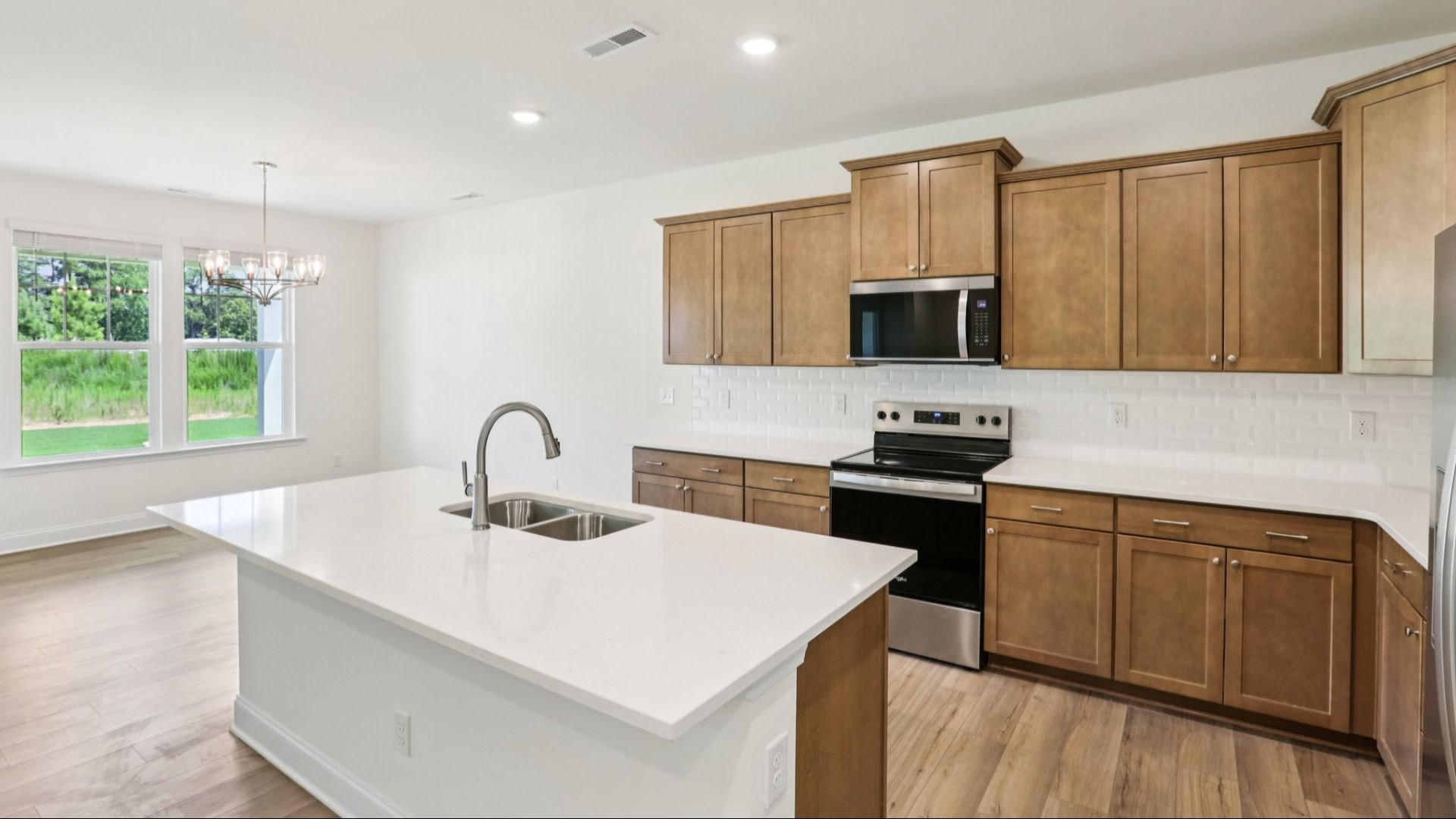 Pendleton home plan open concept kitchen with large island, tile backsplash and abundant cabinetry