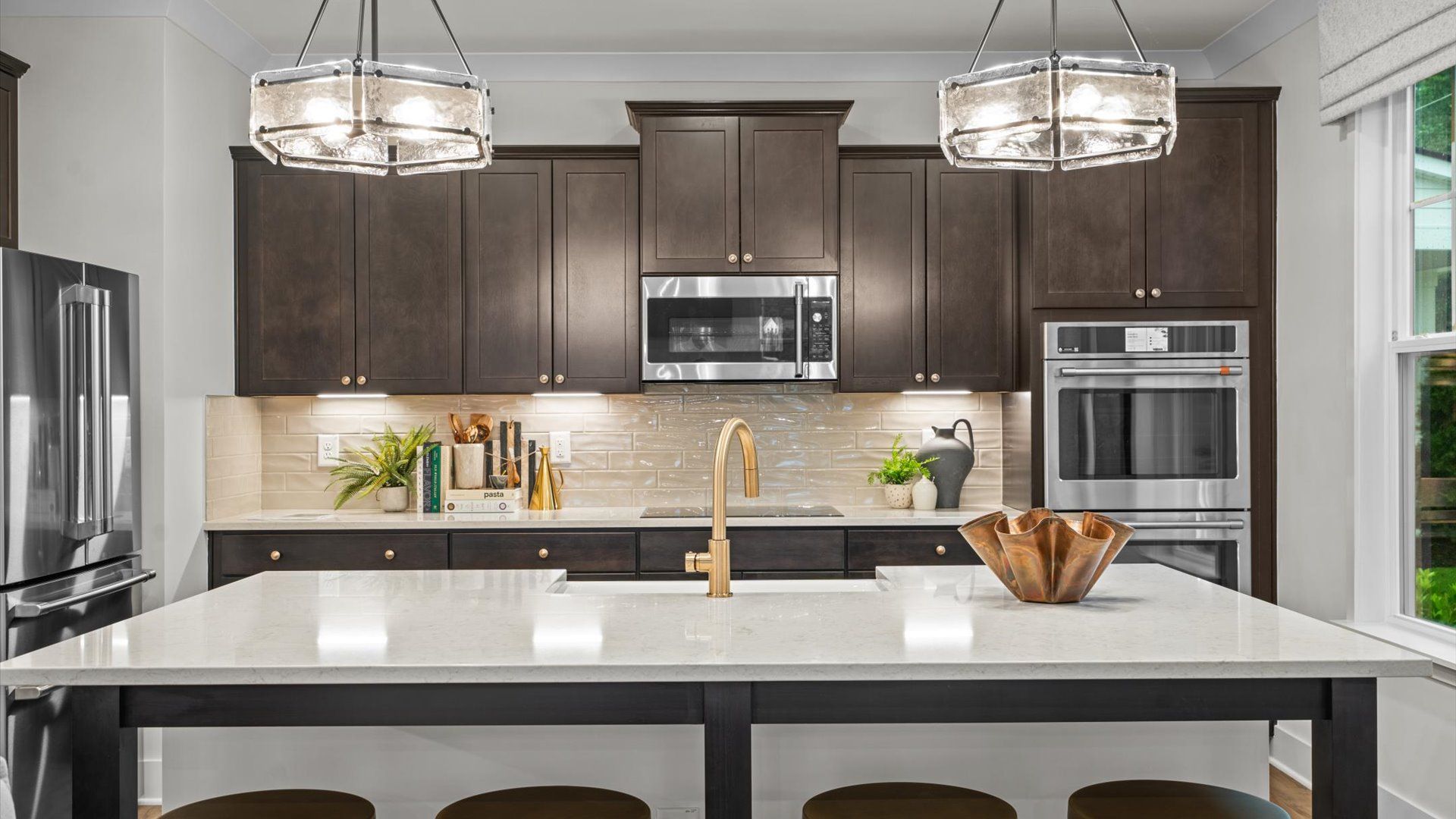 Pelham home plan kitchen with oversized island, tile backsplash, dark cabinetry