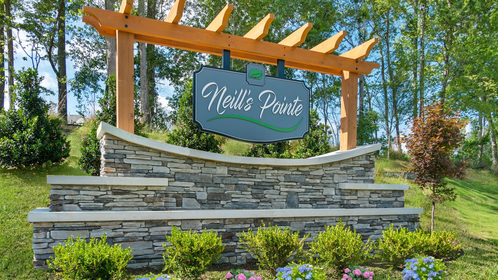 Neill's Pointe community entrance sign in a green lawn with trees and flowers view.