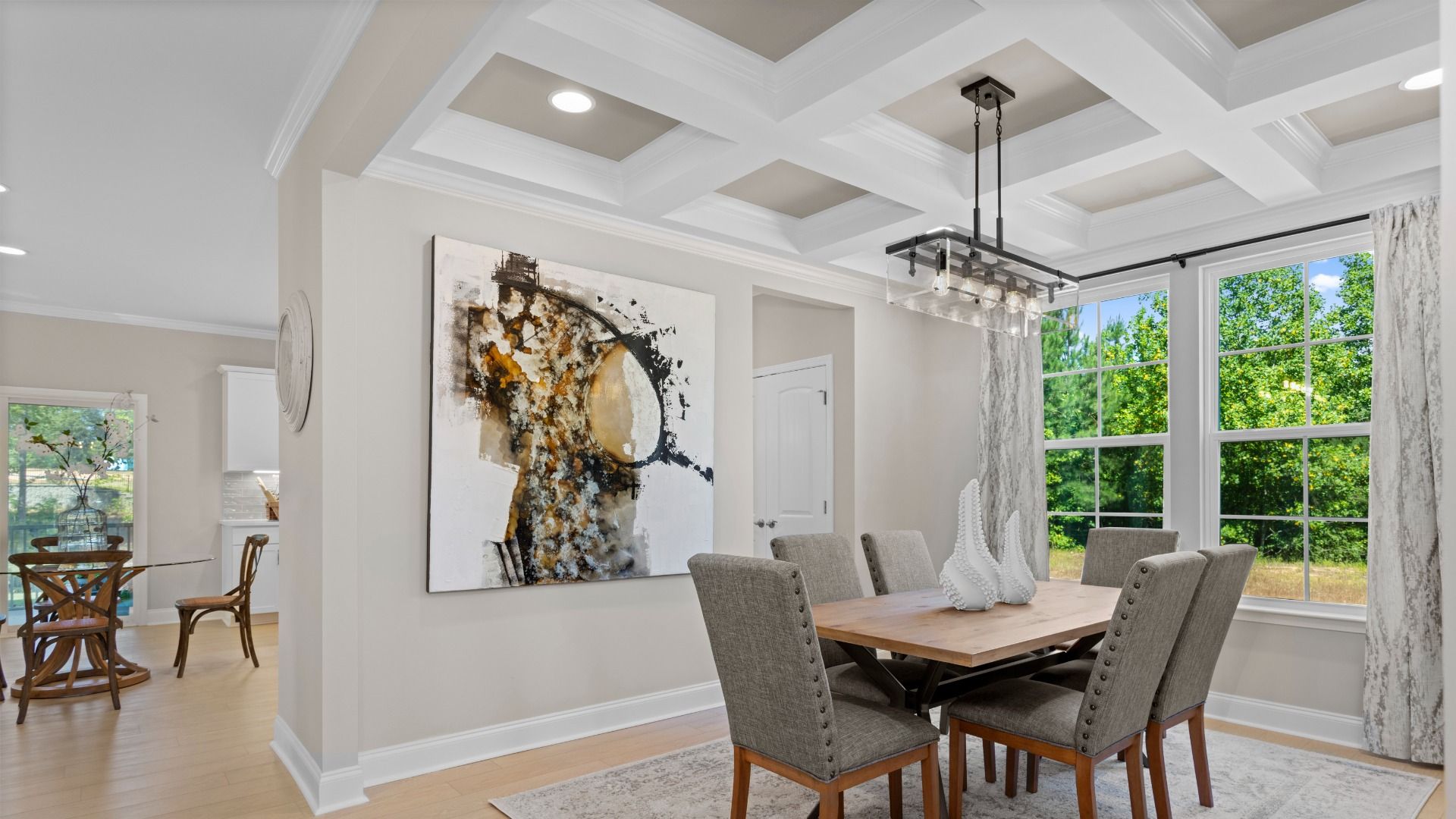 Dining room featuring coffered ceiling, large windows, and pendant light in Neill's Pointe community.
