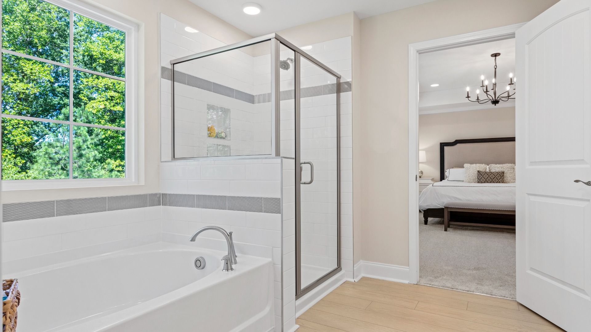 Owner's bathroom with white soaking bathtub, large window, and a separate shower.