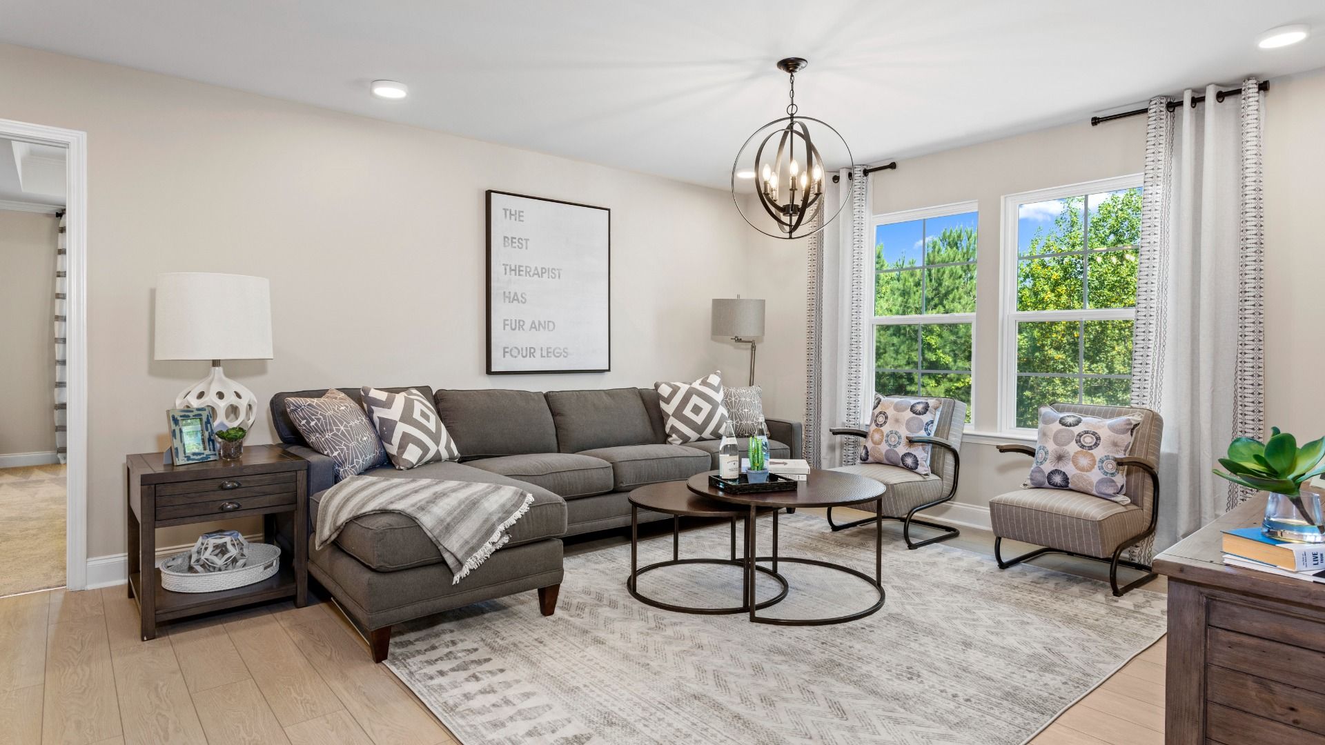 Living room with large windows, seating, and pendant light in the Drayton model home in Angier, NC.