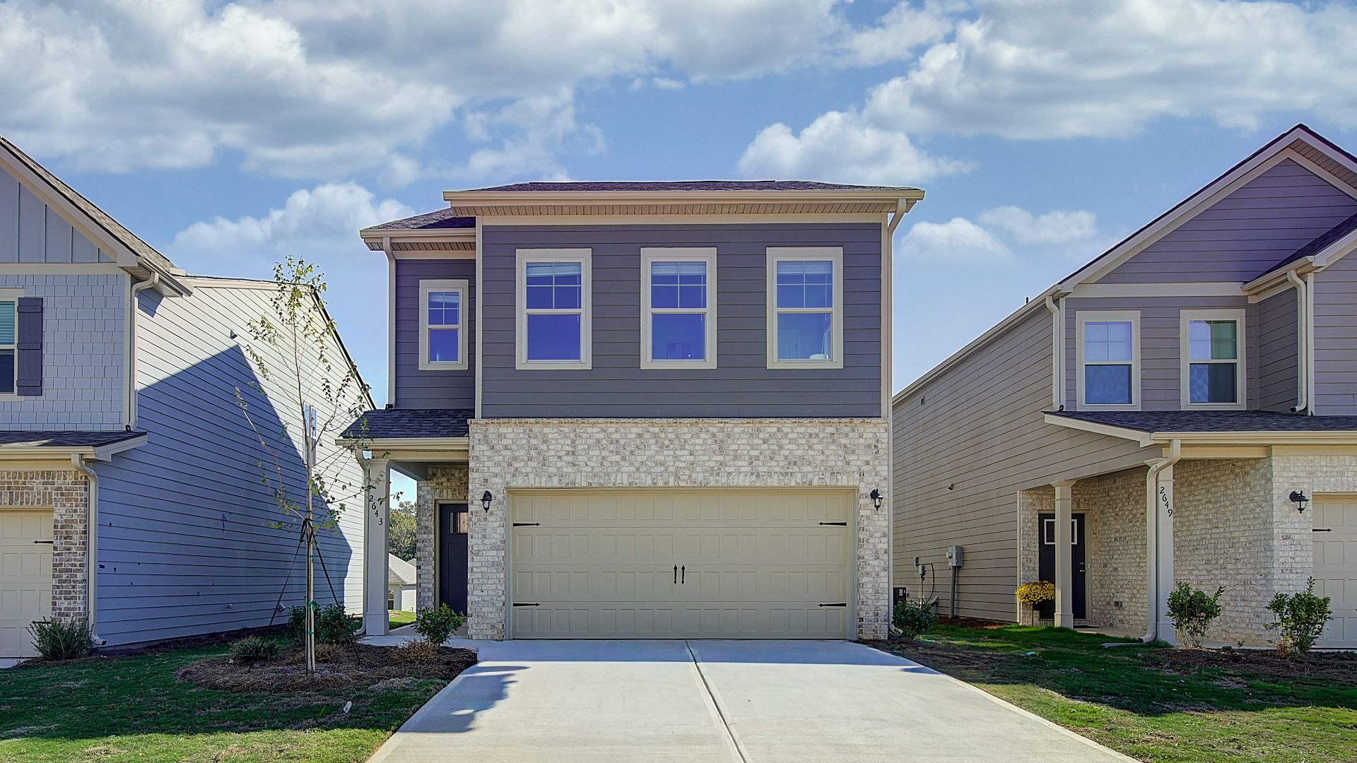 Exterior of new construction single-family home with brick façade, covered entry, and two-car garage in Opelika, AL.