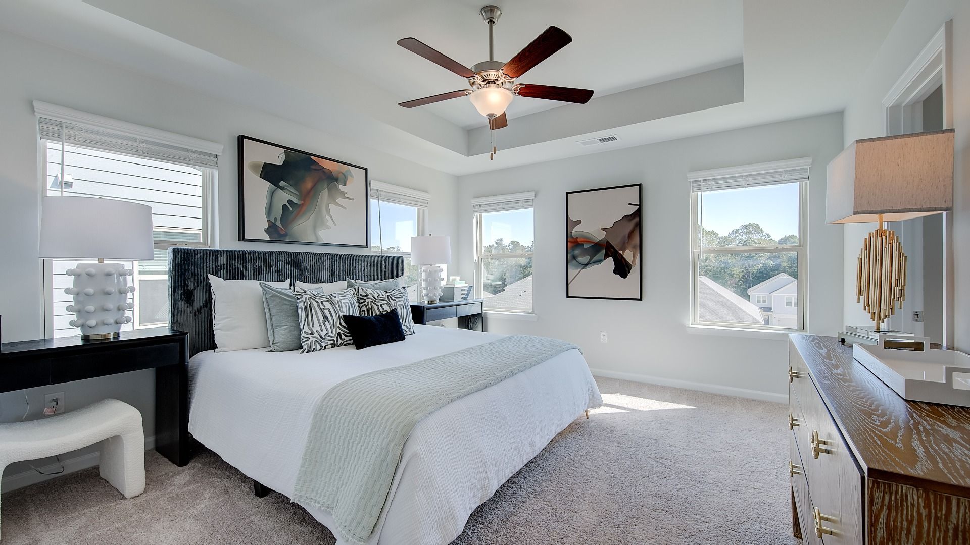 Inviting primary suite with ceiling fan, ample daylight, and modern finishes in new construction home in Opelika, AL.