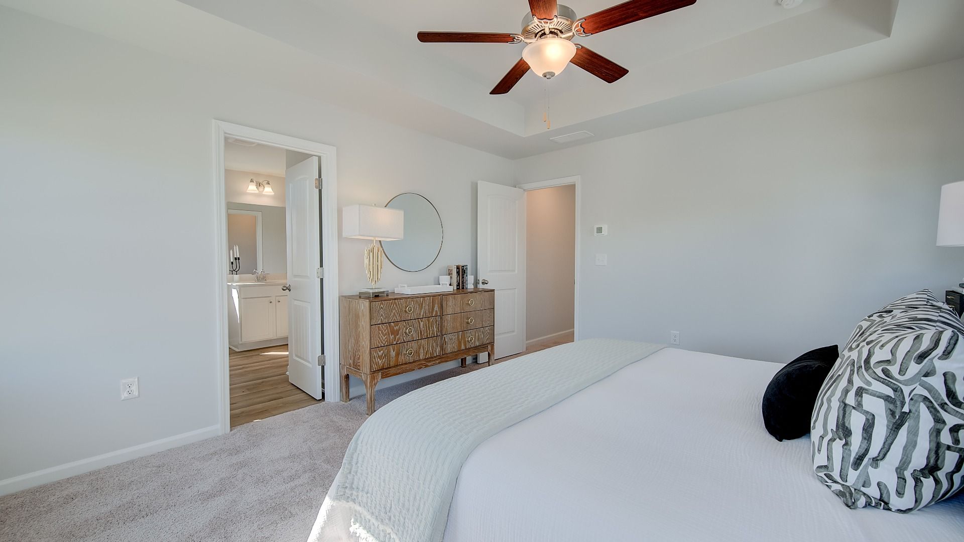 Inviting primary suite with ceiling fan, ample daylight, and modern finishes in new construction home in Opelika, AL.