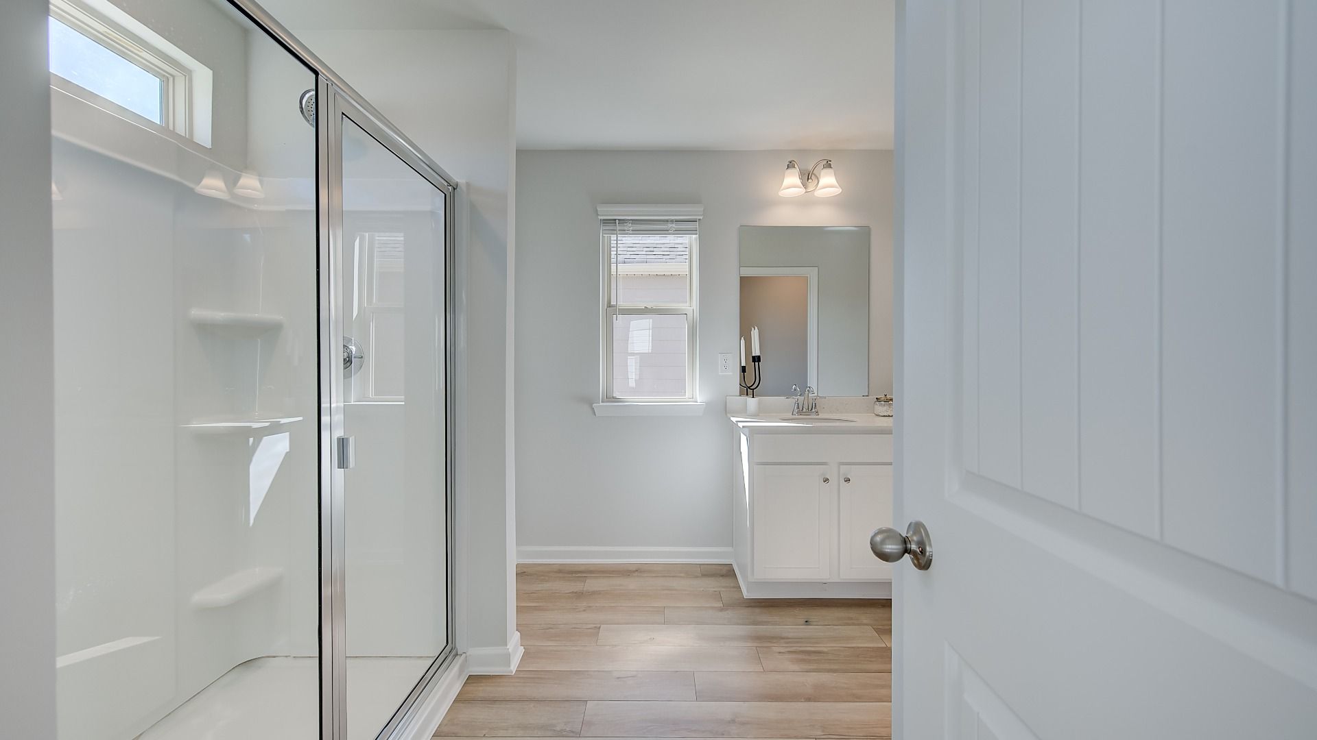 Primary bathroom with dual vanities, large walk-in shower, and modern quartz countertops in new construction home.