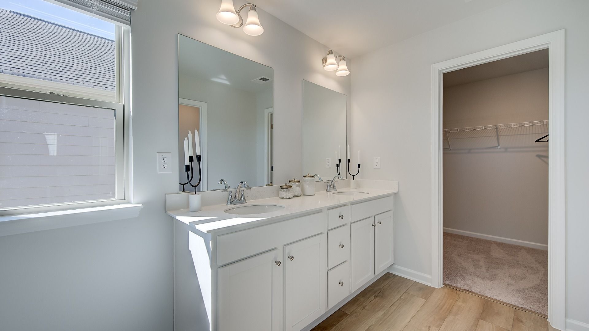 Primary bathroom with dual vanities, large walk-in shower, and modern quartz countertops in new construction home.